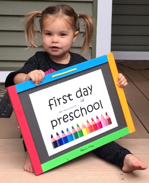 Little girl holding First Day of Preschool sign.