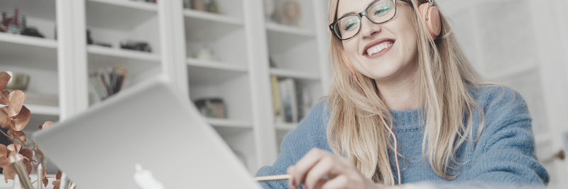 Woman writing while looking at Zoom on the laptop