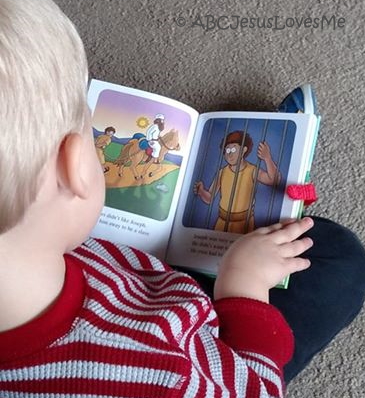 Little boy looking at a children's Bible