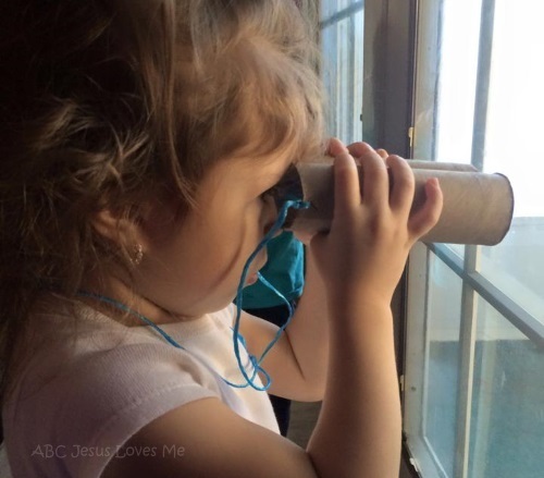 Little girl looking through paper binoculars.