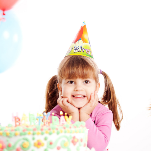 Little girl wearing a birthday hat at birthday party.