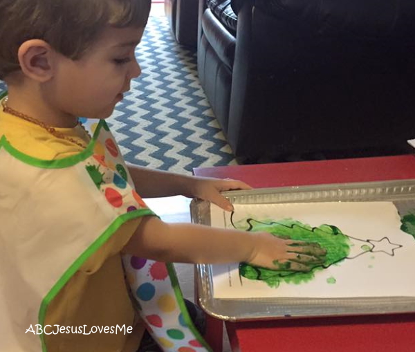 Boy fingerprinting a Christmas tree worksheet.