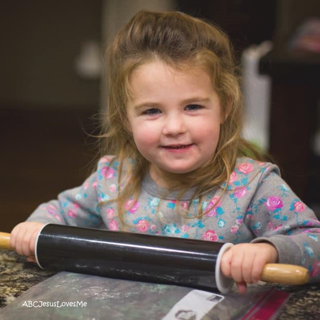 Little girl using a rolling pin.