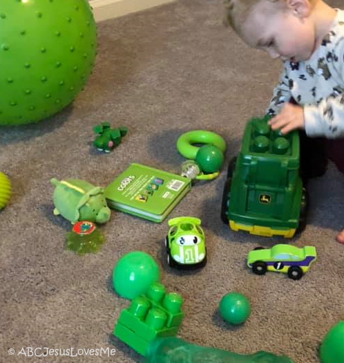 Little boy playing with green toys.
