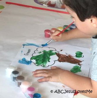 Little boy painting a Creation worksheet