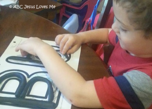 Little boy playing with play dough on Letter Posters.