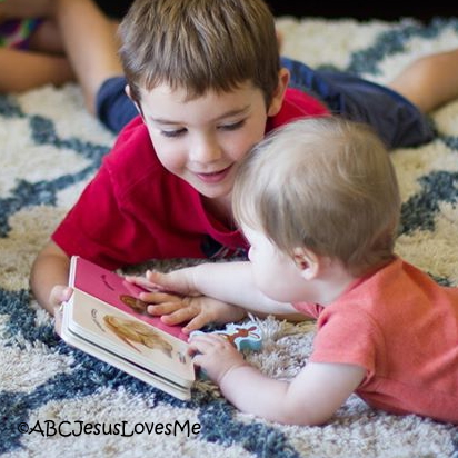 Boy and baby sister reading a book together.